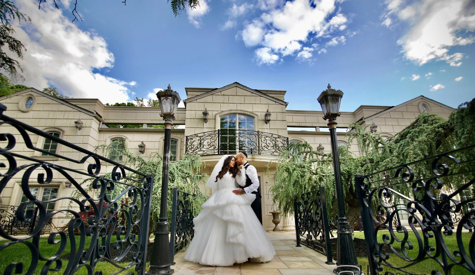 Bride and groom embracing on the garden path of a luxury estate